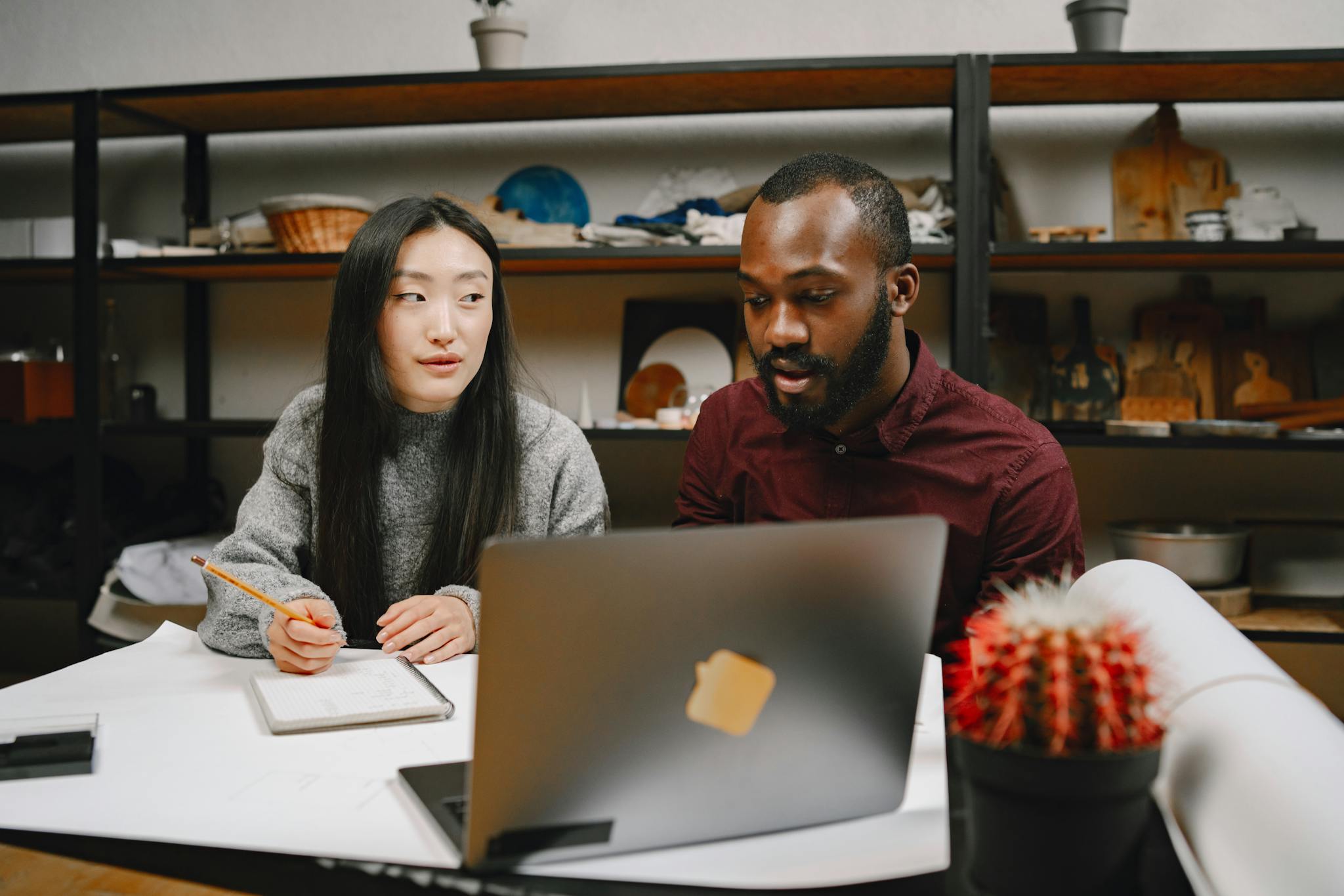 Two colleagues collaborating in a modern workspace with a laptop and notes, fostering creativity and teamwork.